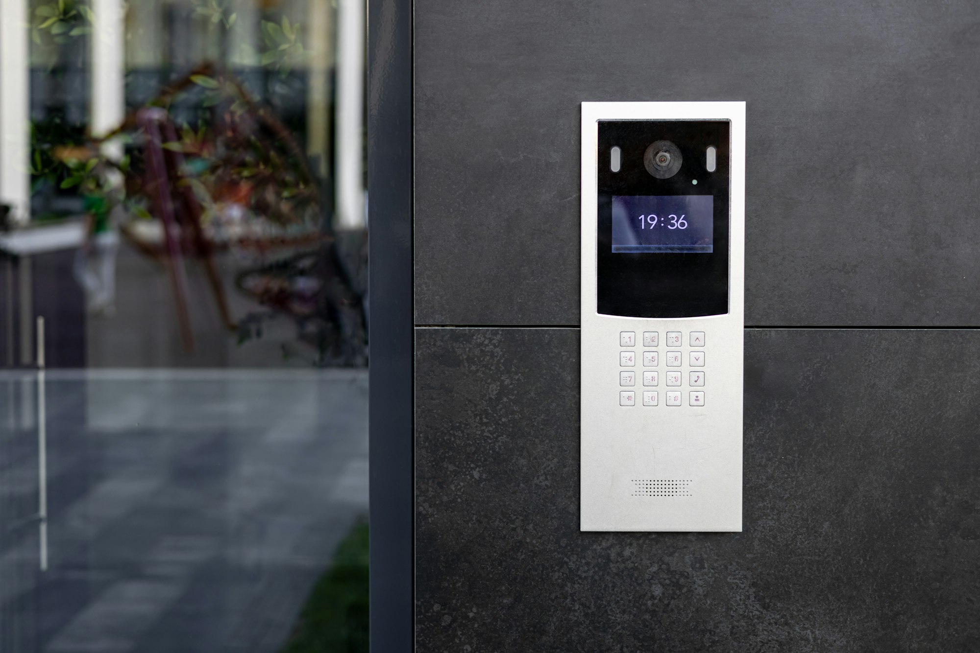 Entrance doorbell in a multi-apartment building, with a video surveillance camera, on a dark wall