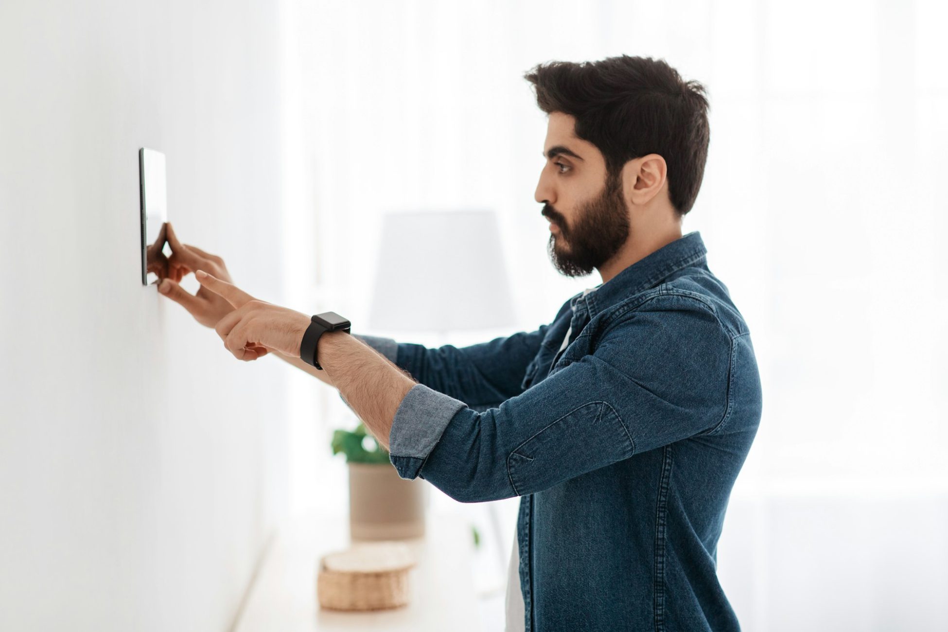 Automation domestic system. Arab man using digital tablet on wall with smart home control system app